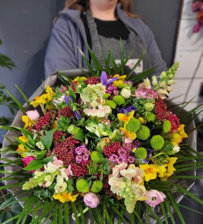 spring quen is mixed spring flowers posy arranged in round shape with mixed colours od spring rununculuses, tulips, narcissus, anemones and complementsry fillers and foliages.